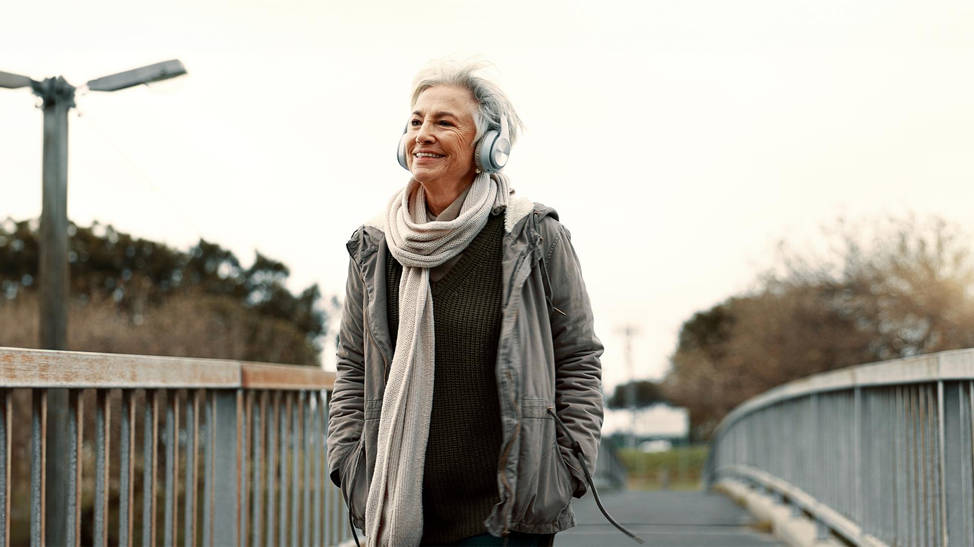 Une femme, casque d’écoute sur la tête, s’informe en écoutant le balado Sans détour lors d’une balade en plein air.
