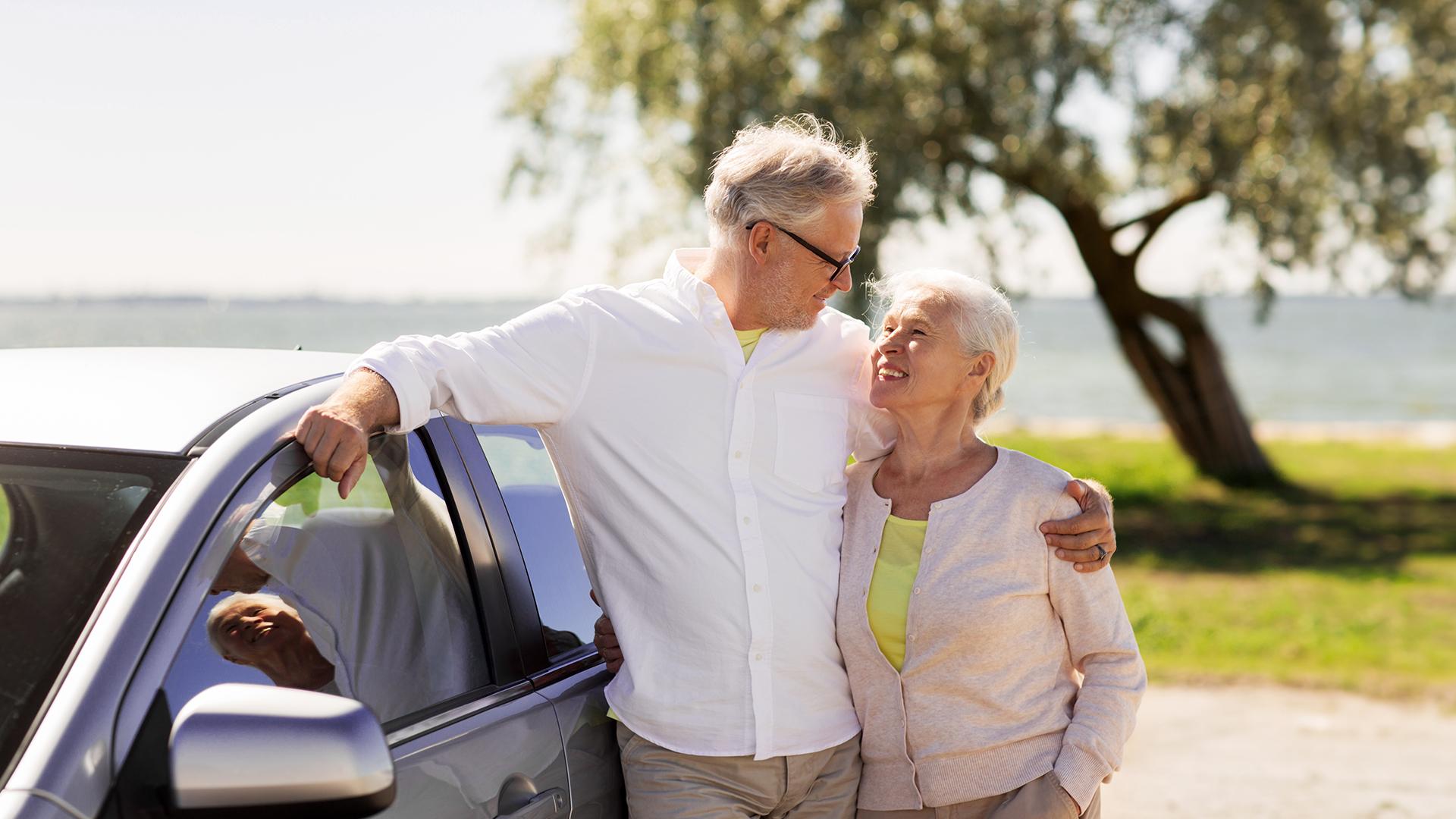 Une aînée au volant de son véhicule sourit pendant que son véhicule est à l’arrêt.