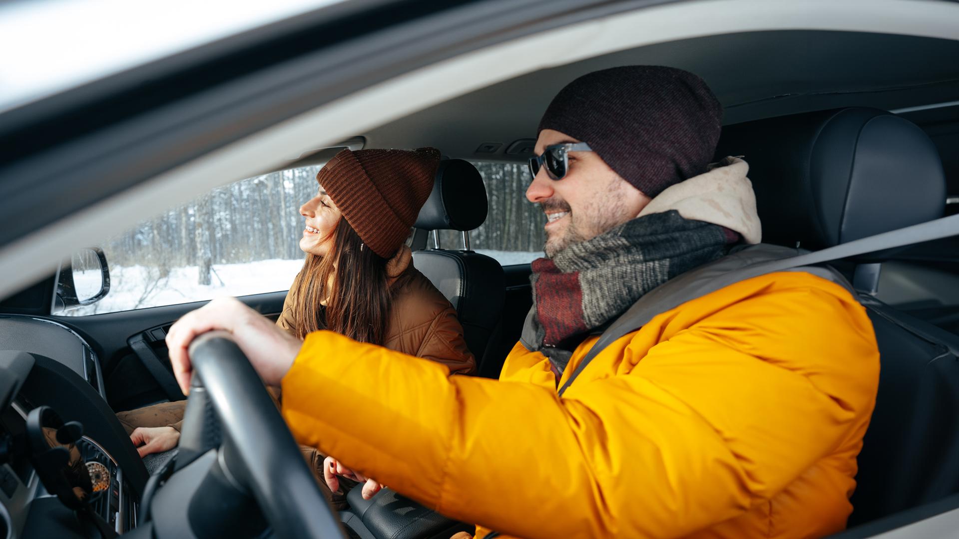 A grandmother holds her grandson in her arms and approaches a vehicle to greet her daughter who’s sitting behind the wheel.